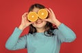 glad teen kid hold orange fruit on purple background