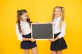 Glad to inform. Schoolgirls informing you. School girls hold blank chalkboard copy space. Girls school uniform hold