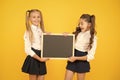 Glad to inform. Schoolgirls informing you. School girls hold blank chalkboard copy space. Girls school uniform hold