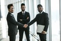 Glad to see you. Two happy young businessmen shaking hands while their colleague smiling in modern office Royalty Free Stock Photo