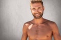 Glad topless male with trendy hairstyle and bristle having strong body builduing posing against grey background with happy express Royalty Free Stock Photo