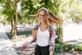 Glad white woman drinkng coffee outdoor while listening music. Outdoor portrait of lovely smiling g