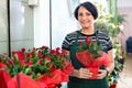 Glad woman florist smiling among the potted plants