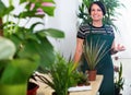 Glad woman florist smiling among the potted plants