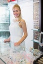 Glad woman seller standing next to glass showcase Royalty Free Stock Photo