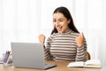Glad young arab woman manager work at computer, celebrate win, success with raise hands