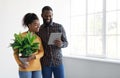 Glad young black male and female moving in new home and planning interior, choose house removal service Royalty Free Stock Photo