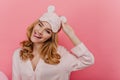 Glad young lady with shiny blonde hair posing with pretty smile. Indoor photo of joyful positive girl in sleepmask