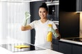 Gladful female doing the housework while using a spray in the kitchen. Young woman showing ok gesture.