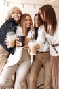 Gladful four young women friends having coffee break while relaxing at the cafe indoors.