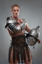 Gladiator in armour posing with helmet over grey Royalty Free Stock Photo