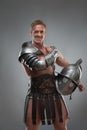 Gladiator in armour posing with helmet over grey Royalty Free Stock Photo