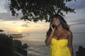 glamorous African American black woman in chic and elegant summer dress talking on mobile phone at sunset beach Royalty Free Stock Photo