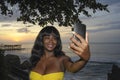 glamorous African American black woman in chic summer dress taking selfie picture or video on mobile phone Royalty Free Stock Photo
