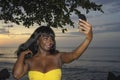 Glamorous African American black woman in chic summer dress taking selfie picture or video on mobile phone Royalty Free Stock Photo