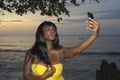 Glamorous African American black woman in chic summer dress taking selfie picture or video on mobile phone Royalty Free Stock Photo