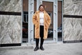 Glamorous african american woman in warm fur coat, eyeglasses pose at street