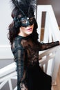 Glamorous brunette lady with a beautiful hairstyle and red lips, in an evening dress, a Venetian black mask with stylish accessori