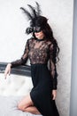 Glamorous brunette lady with a beautiful hairstyle and red lips, in an evening dress, a Venetian black mask with stylish accessori