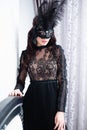 Glamorous brunette lady with a beautiful hairstyle and red lips, in an evening dress, a Venetian black mask with stylish accessori