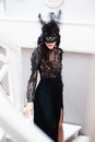 Glamorous brunette lady with a beautiful hairstyle and red lips, in an evening dress, a Venetian black mask with stylish accessori