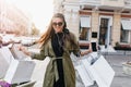 Glamorous dark-haired lady with smartphone walking down the street after morning shopping. Outdoor portrait of cute Royalty Free Stock Photo