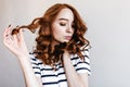 Glamorous ginger woman with stylish makeup posing on light background. Indoor photo of red-haired f Royalty Free Stock Photo