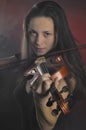 Glamorous girl with a long brown hair playing the violin Royalty Free Stock Photo