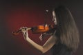 Glamorous girl with a long brown hair playing the violin