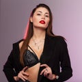 Glamorous portrait young beautiful woman with sexy red lips with long chic brown hair in lace underwear in stylish black coat in Royalty Free Stock Photo