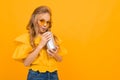 Glamorous teenager in bright glasses drinks a cocktail on a yellow wall with copy space Royalty Free Stock Photo