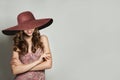 Glamorous Woman in Summer Dress and wide pink broad brim hat against White Wall Background, Fashion