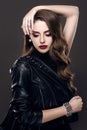 Glamorous young beautiful rock style girl in black leather jacket with accessories on dark gray background Royalty Free Stock Photo