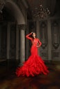Glamorous young brunette model woman in red evening gown standing in luxurious interior Royalty Free Stock Photo