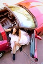Glamorous Young Woman Getting Out of Red Sports Car