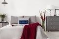 Glamour bedroom interior with a bed dressed in gray linen and cushions with contrasting accents of blue and red. Royalty Free Stock Photo