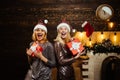 Glamour celebration new year. Blonde Santa woman holding gift box at vintage wall. Portrait of beautiful two girls Royalty Free Stock Photo
