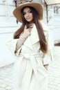 Glamour girl with dark straight hair wears luxurious beige coat with elegant hat,