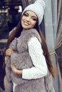 Glamour girl with dark straight hair wears luxurious fur coat and knitted hat