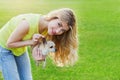 Glamour happy smiling girl or woman holding cute chihuahua puppy dog on green lawn on the sunset