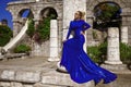 Glamour, stylish elegant woman in blue long evening gown dress is posing near the pool in luxury resort outdoor Royalty Free Stock Photo