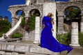 Glamour, stylish elegant woman in blue long evening gown dress is posing near the pool in luxury resort outdoor Royalty Free Stock Photo