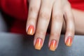 Glamour woman hand with orange nail polish on her fingernails. Orange color nail manicure with gel polish at luxury beauty salon.