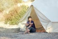 Glamping outdoor vacation. Woman drinking tea near big camping tent with cozy interior. Luxury travel accomodation into the forest Royalty Free Stock Photo