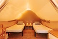 Glamping tent cozy interior with beds on a sunny day. Glamorous camping tent for outdoor summer holiday and vacation lifestyle