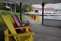 Multi coloured Muskoka Chairs inside the patio gazebo and other at the lake front of the tourist resort