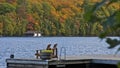 Retirement Living - Two Muskoka chairs sitting on a boat dock autumn leaf color and a boathouse in the background