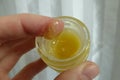 Glance into a round jar with a shiny yellow ointment . The index finger is smeared with a bit of the cream . Ugly butter or