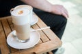 Glas of Latte Macchiato and cup of Cappuccino coffee with milk on wooden table outside of street caf