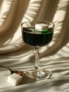 Glass of absinthe with sugar cube, spoon on draped background. Royalty Free Stock Photo
